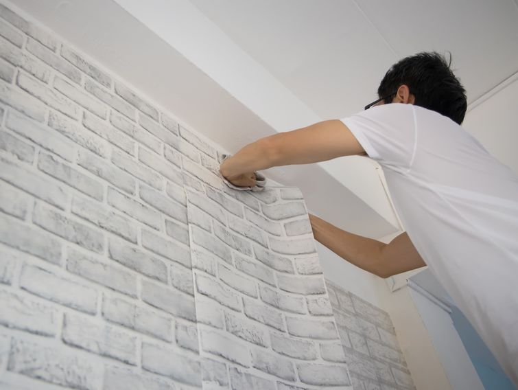 Handyman putting up wallpaper in the room which renovation his home