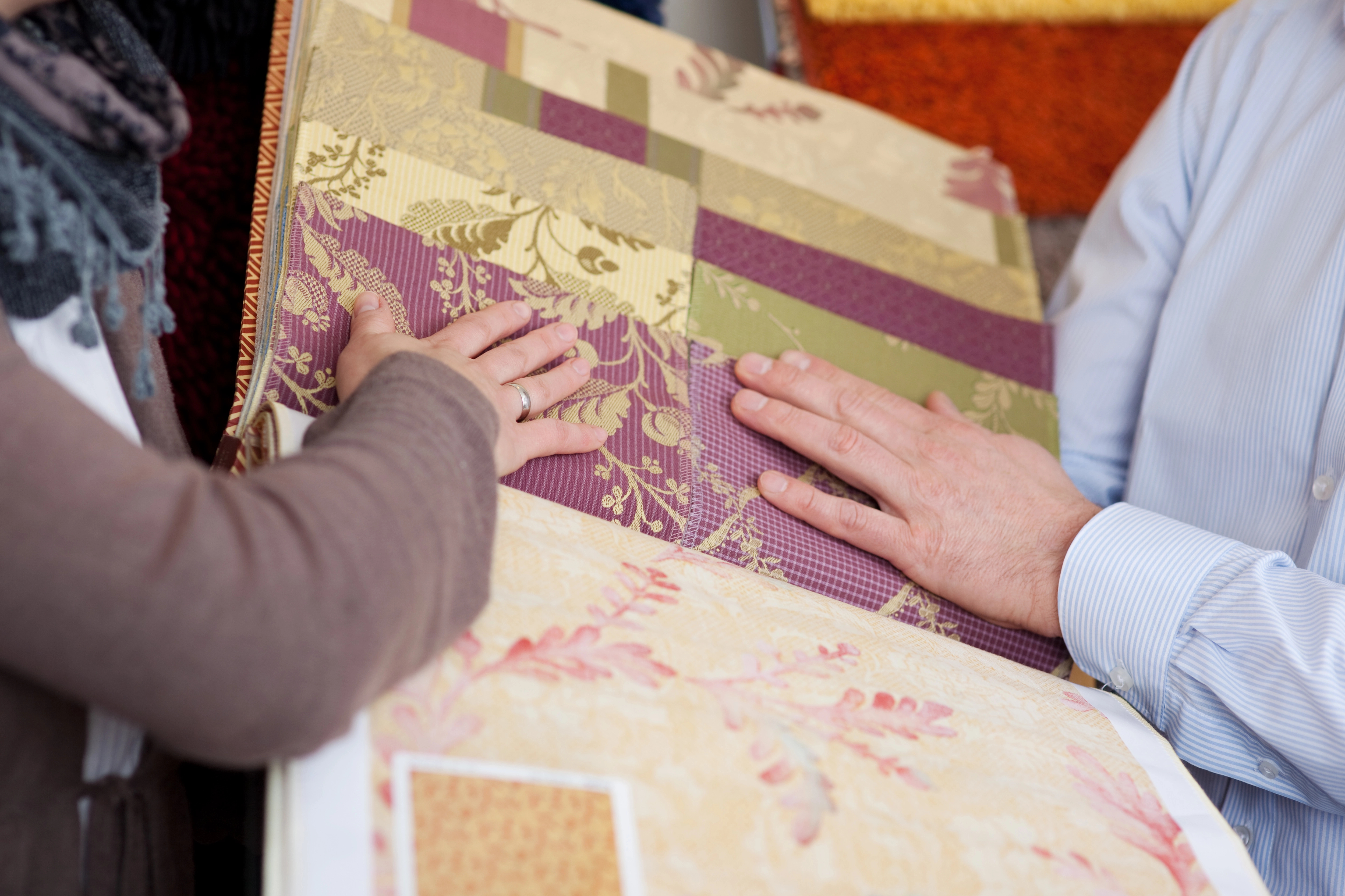Woman examining wallpaper and fabric swatches for selection